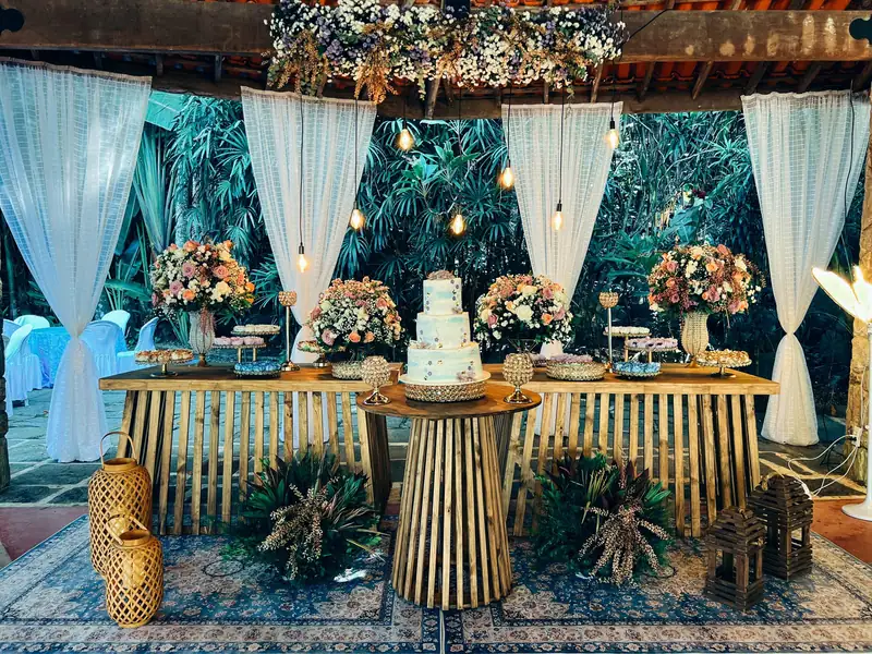 Mesa de bolo e doces com flores e cortinas no salão