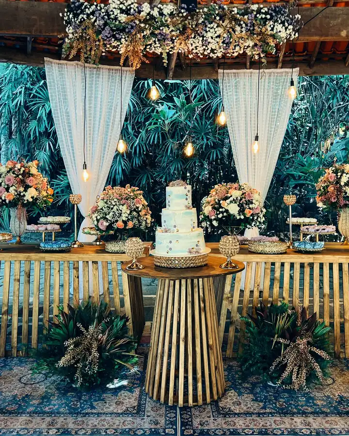 Mesa de bolo e doces com flores e cortinas no salão